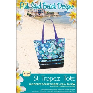 May include: A tote bag with a floral pattern in shades of blue and turquoise, with a black base and purple handles. The bag is labeled "St Tropez Tote" and includes the text "BIG ZIPPER POCKET INSIDE • EASY TO SEW".