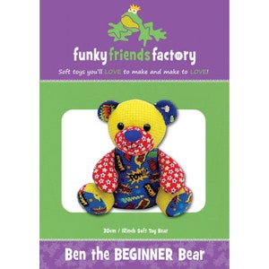 May include: A soft toy bear with a yellow head, blue ears, and red and blue patterned arms and legs. The bear's chest features a comic book design with the words "POW!" and "ZOOM!". The packaging reads "Ben the BEGINNER Bear" and measures 12 inches.