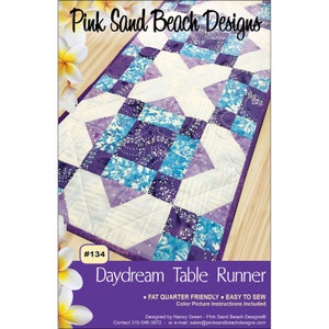 May include: A quilted table runner with a Daydream pattern, featuring a mix of purple, blue, and white fabrics. The design includes geometric shapes and a central starburst pattern. The text "Pink Sand Beach Designs" and "Daydream Table Runner" are visible.
