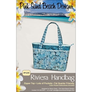 Puede incluir: Un bolso Riviera de color turquesa con un estampado de cachemira, ribete blanco y asas a juego. El bolso tiene una cremallera y está diseñado por Pink Sand Beach Designs. El texto "#125" y "Riviera Handbag" está incluido.
