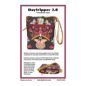 May include: A Daytripper 2.0 crossbody case with a brown background and a colorful floral design. The bag has a zippered top, front pocket, and adjustable strap. The text "Daytripper 2.0 Crossbody Case" is at the top.
