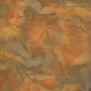 May include: Textile artwork with an abstract design. The fabric displays a mix of warm colours, including orange, tan, and light brown. The textured surface creates a layered effect. The design has a soft, organic feel with subtle variations in tone and shading.