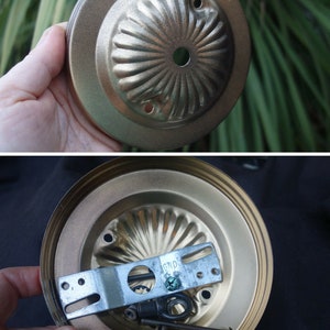 Puede incluir: Luminaria de techo de metal de color dorado con un diseño decorativo acanalado. La luminaria tiene un soporte de montaje y tornillos para la instalación.