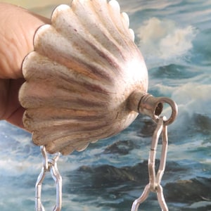 May include: A silver-toned metal ceiling fixture with a scalloped design and a chain hanging from it.