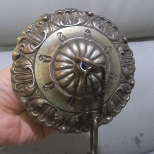 May include: A silver ceiling fixture with an ornate design and a chain hanging from the center.