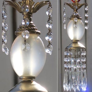 May include: A vintage-style chandelier with a frosted glass globe and crystal accents. The chandelier has a gold-tone finish and features a decorative design on the top.