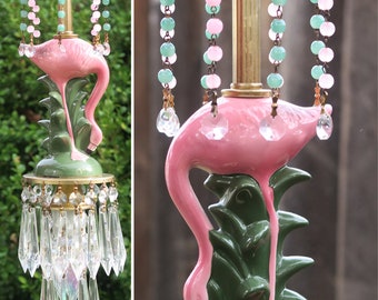 May include: Pink flamingo ceramic chandelier with green leaves, crystal drops, and pink and green beaded strands.