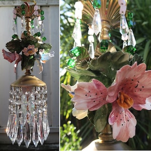 May include: A vintage chandelier with a floral design. The chandelier features pink and white porcelain flowers, green leaves, and crystal drops.
