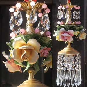 May include: A gold chandelier with pink and white porcelain roses and crystal drops.