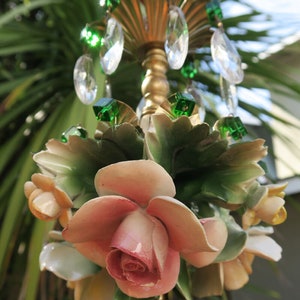 May include: A vintage chandelier with a floral design. The chandelier features a cluster of pink and white porcelain roses with green leaves. The chandelier is adorned with crystal drops and green glass beads.