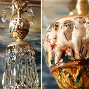 May include: A vintage brass and ceramic chandelier with a detailed cherub design and crystal accents. The ceramic globe features a scene of three cherubs with painted details.