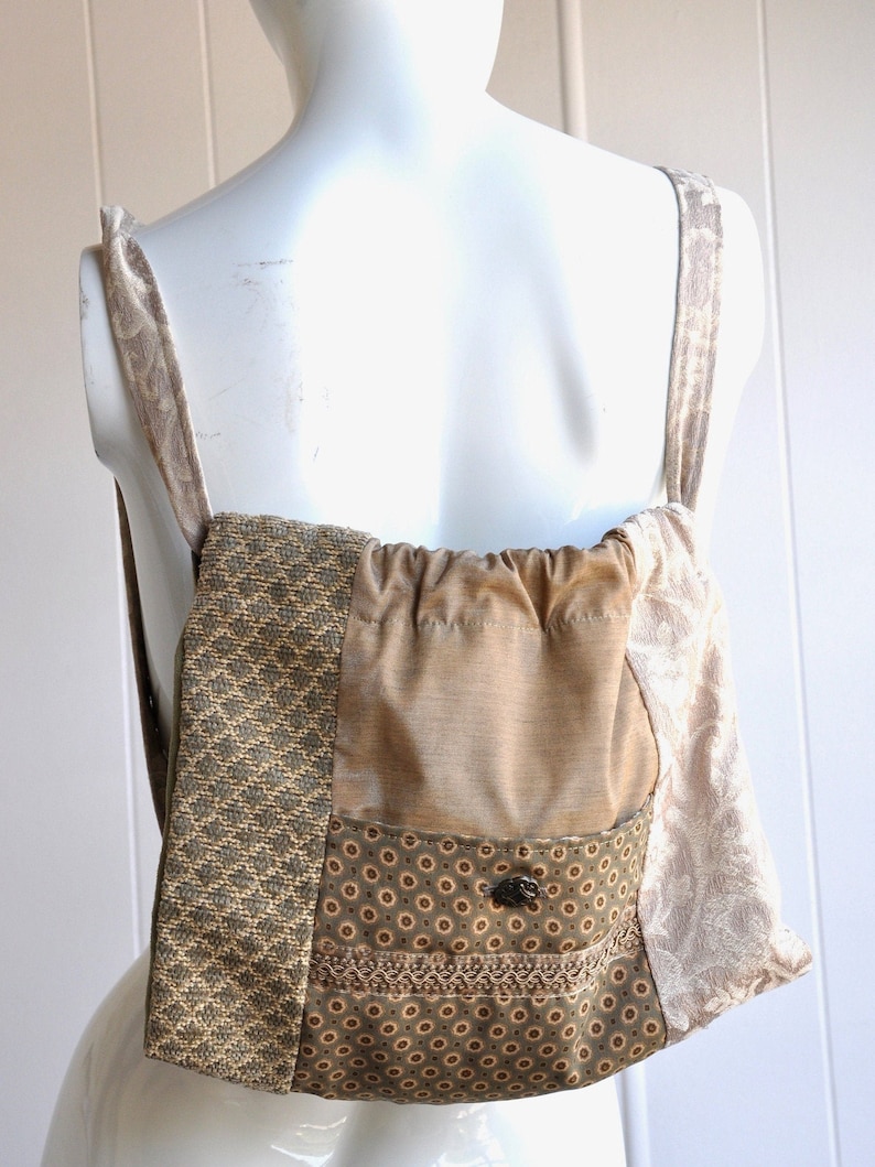 Puede incluir: Una mochila de tela de patchwork marr&oacute;n y beige con cierre de cord&oacute;n y un peque&ntilde;o bolsillo en la parte delantera. La mochila tiene un estampado floral y un cierre de bot&oacute;n.