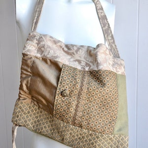 Puede incluir: Un bolso tote de patchwork con una combinaci&oacute;n de colores verde, marr&oacute;n y beige. El bolso tiene una sola correa y est&aacute; hecho de diferentes telas con varios patrones.