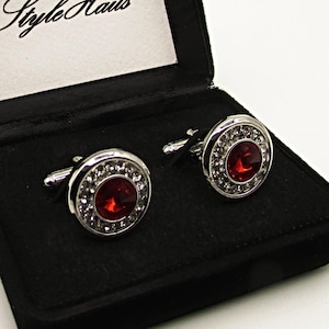May include: Two silver cufflinks with red crystal accents in a black velvet box with the text "Style Haus" on the lid.