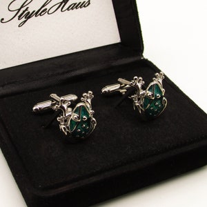 May include: A black velvet box with the words "Style Haus" on the lid. The box contains two silver cufflinks with green frog designs.