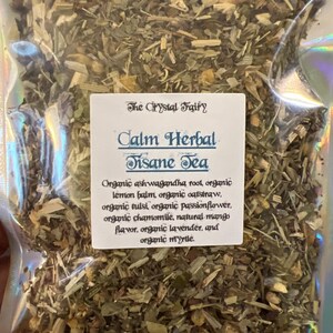 May include: A clear plastic bag filled with dried herbs and labeled "Calm Herbal Tisane Tea" by The Crystal Fairy. The label lists ingredients like organic ashwagandha root, lemon balm, oatstraw, tulsi, passionflower, chamomile, mango flavor, lavender, and myrtle.