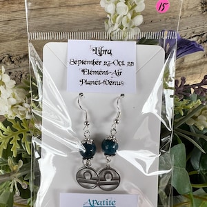 May include: A pair of silver Libra earrings with blue apatite beads. The card reads "Libra September 23-Oct. 22 Element-Air Planet-Venus Apatite Psychic Activation, Access to knowledge, Calming".