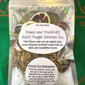 Könnte beinhalten: Ein weißer Beutel mit Reißverschluss, der eine Mischung aus getrockneten Kräutern, Gewürzen und Epsom-Salzen enthält. Der Beutel trägt ein Etikett mit der Aufschrift "Peace and Positivity Fairy Magic Simmer Pot" und enthält eine Liste der Zutaten: Nelken, Zimt, Lavendel, Kamille, Limettenscheiben und Eukalyptusblätter. Das Etikett enthält auch Anweisungen zur Verwendung des Simmer Pots.