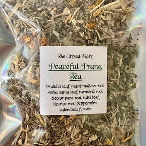 Puede incluir: Una bolsa transparente llena de hierbas y hojas secas. Una etiqueta blanca dice "The Crystal Fairy Peaceful Prana Tea" con una lista de ingredientes, incluyendo hoja de gordolobo y raíz de malvavisco. Una mezcla de té de hierbas naturales.