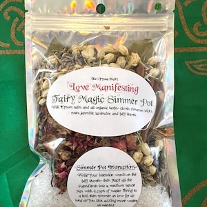 Könnte beinhalten: Ein durchsichtiger Plastikbeutel gefüllt mit getrockneten Kräutern, Blumen und Epsom-Salzen. Der Beutel ist mit "Love Manifesting Fairy Magic Simmer Pot" beschriftet und enthält Anweisungen zur Verwendung. Der Beutel befindet sich auf einem grünen Hintergrund.