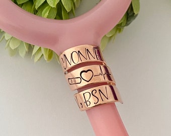 Könnte beinhalten: Ein Stethoskop-Anhänger aus Roségold mit dem Namen "Yvonne", einem Herzen, einer Herzschlaglinie und den eingravierten Buchstaben "BSN".