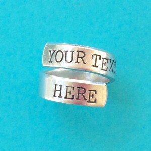May include: A silver ring with the words "YOUR TEXT HERE" engraved on it.
