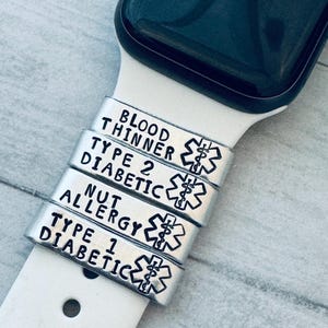 以下が含まれることがあります： スマートウォッチバンド用のシルバーメディカルアラートチャーム。チャームには、血液シンナー、2型糖尿病、ナッツアレルギー、1型糖尿病の条件が刻印されています。各チャームには医療シンボルが付いています。