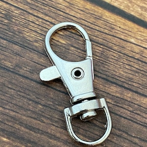 May include: A silver metal key chain clip with a swivel hook and a D-ring.