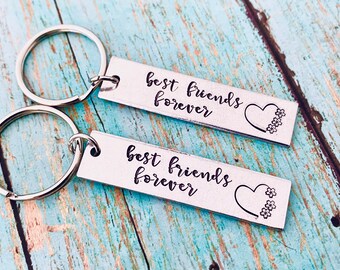 May include: Two silver keychains with the text "best friends forever" and a heart with flowers engraved on each.