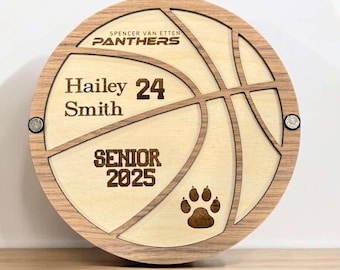 Puede incluir: Una placa de madera con forma de balón de baloncesto con el texto "Spencer Van Etten Panthers" en la parte superior, "Hailey Smith 24" en el centro y "Senior 2025" en la parte inferior. Una huella de pata se encuentra en la esquina inferior derecha.