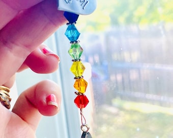 May include: A crystal suncatcher with a rainbow of beads and a silver heart charm with the name "Rascal" engraved on it.