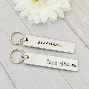 May include: Two silver keychains with engraved messages. The top keychain says "gracelynn" and the bottom keychain says "love you" with a small heart symbol.