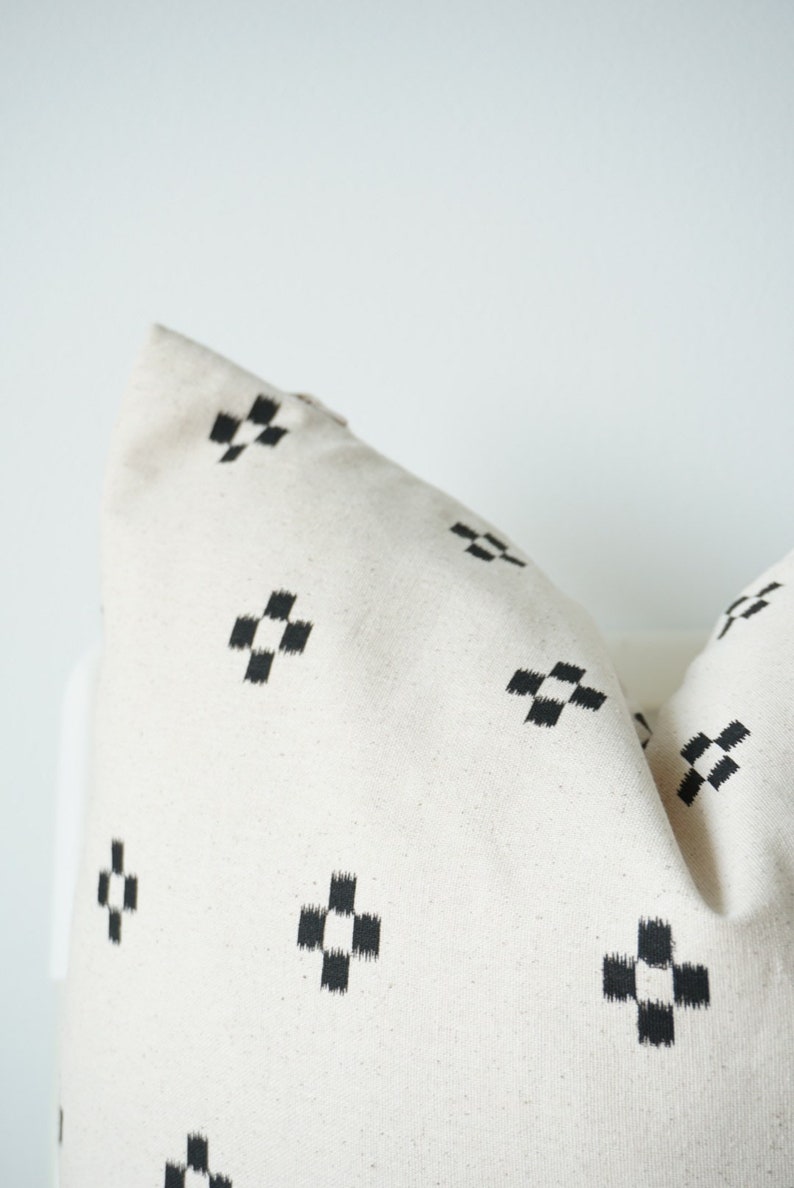 May include: A white pillow with a black and white geometric pattern. The pattern is a series of small squares arranged in a cross shape.