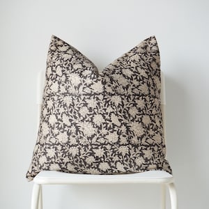 Puede incluir: Una silla blanca con un coj&iacute;n de estampado floral negro y crema en el asiento.