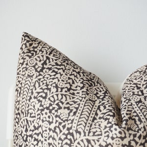 May include: A black and white patterned pillow with a floral design. The pillow is made of a soft, textured fabric.
