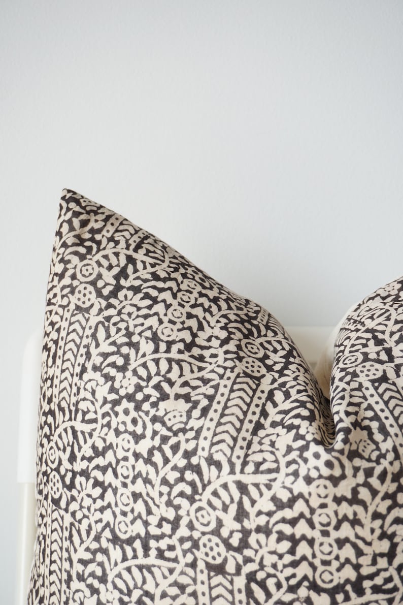 May include: A black and white patterned pillow with a floral design. The pillow is made of a soft, textured fabric.