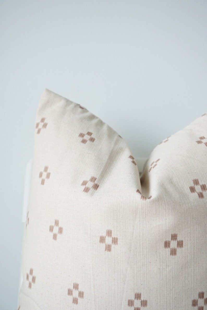 May include: A white pillow with a brown geometric pattern. The pillow is made of a soft, textured fabric.