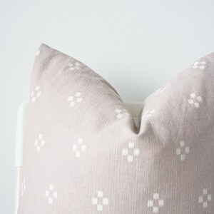 May include: A light gray throw pillow with a white geometric pattern. The pillow is made of a soft, textured fabric.