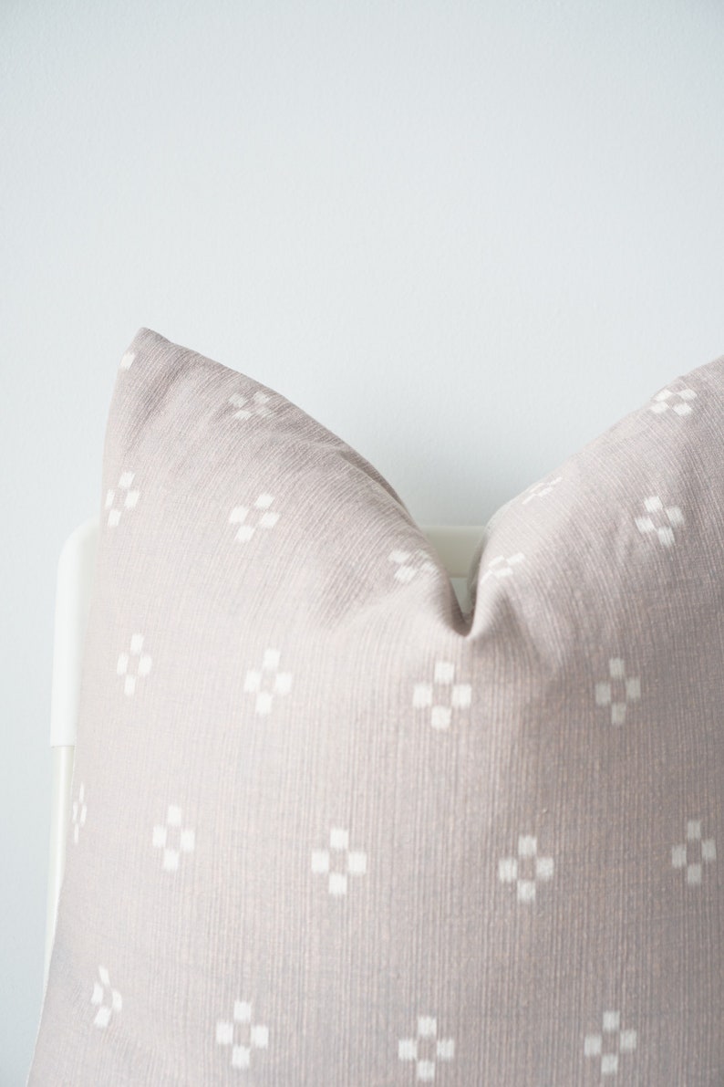 May include: A light gray throw pillow with a white geometric pattern. The pillow is made of a soft, textured fabric.
