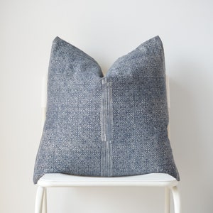 May include: A blue and white patterned throw pillow on a white chair. The pillow has a geometric design.