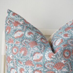 Puede incluir: Un par de fundas de almohada azul turquesa con un patr&oacute;n floral en tonos de rosa y blanco.