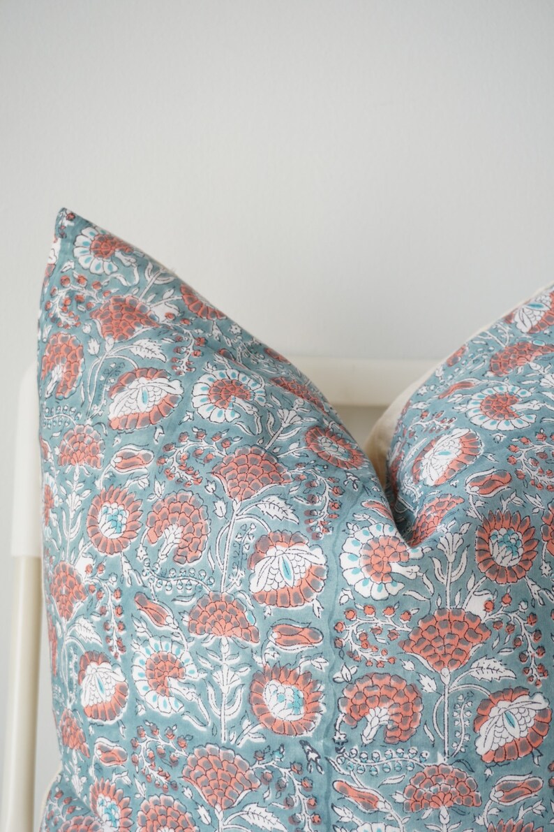 Puede incluir: Un par de fundas de almohada azul turquesa con un patr&oacute;n floral en tonos de rosa y blanco.