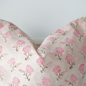 May include: A pink and green floral patterned pillow cover. The pillow cover is made of a soft, light fabric and features a delicate floral design.
