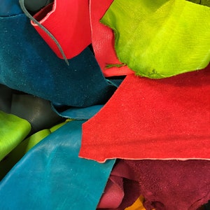 Pu&ograve; includere: Un mucchio di ritagli di pelle colorati in tonalit&agrave; di rosso, verde, blu, giallo e viola. La pelle &egrave; disposta in un motivo casuale, con alcuni pezzi che si sovrappongono ad altri.