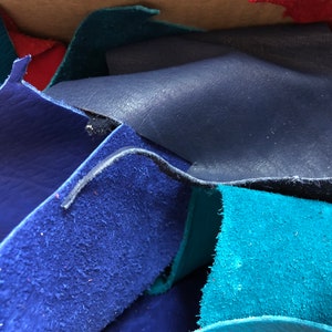 Pu&ograve; includere: Primo piano di un mucchio di ritagli di pelle in varie tonalit&agrave; di blu e turchese. La pelle &egrave; testurizzata e sembra essere scamosciata.