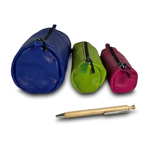 Może przedstawiać: Trzy skórzane piórniki w różnych rozmiarach i kolorach: niebieski, zielony i różowy. Piórniki są ustawione od największego do najmniejszego.