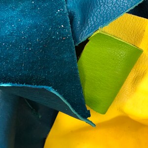 Pu&ograve; includere: Primo piano di tre pezzi di pelle di diversi colori: verde acqua, giallo e verde. La pelle &egrave; testurizzata e ha un aspetto naturale.
