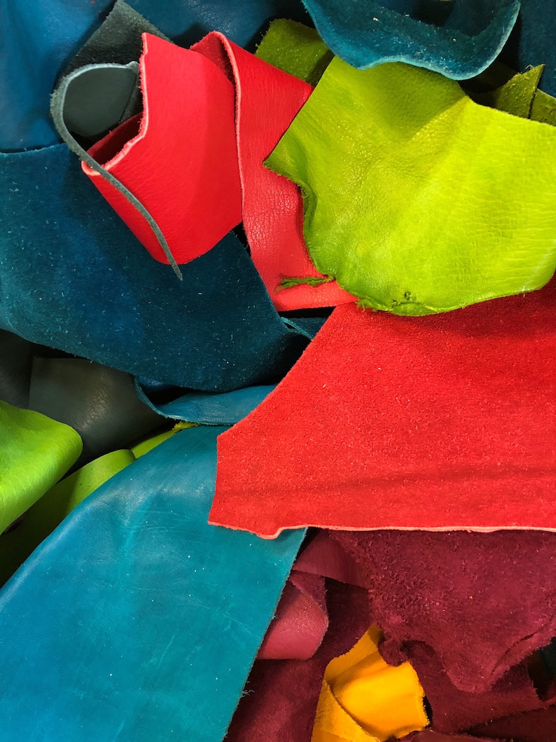 Pu&ograve; includere: Un mucchio di ritagli di pelle colorati in tonalit&agrave; di rosso, verde, blu, giallo e viola. La pelle &egrave; disposta in un motivo casuale, con alcuni pezzi che si sovrappongono ad altri.