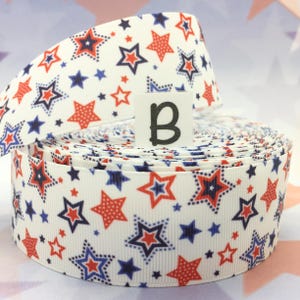 May include: A roll of white ribbon with a red, white, and blue star pattern. The ribbon is 1.5 inches wide and is perfect for crafting, decorating, and adding a festive touch to any project.