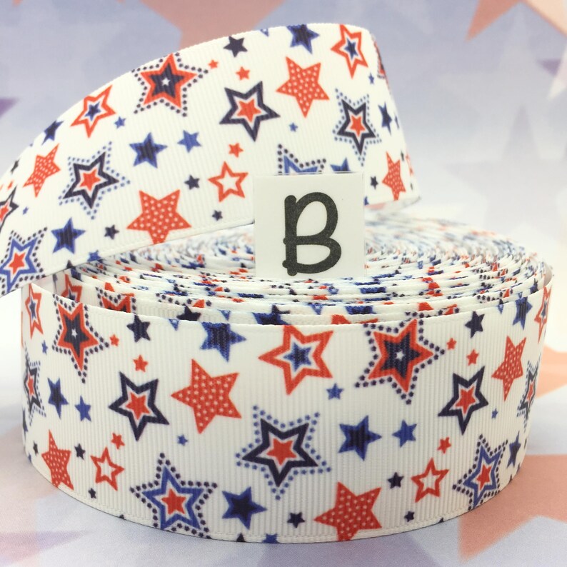 May include: A roll of white ribbon with a red, white, and blue star pattern. The ribbon is 1.5 inches wide and is perfect for crafting, decorating, and adding a festive touch to any project.